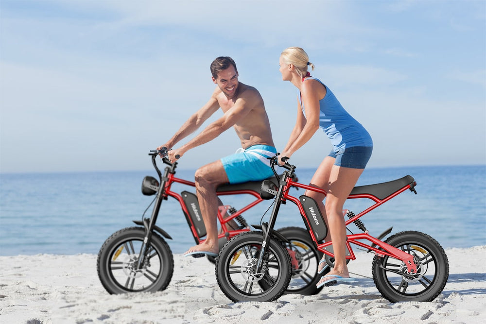 A young couple riding fat tire electric bike on the beach in the summer